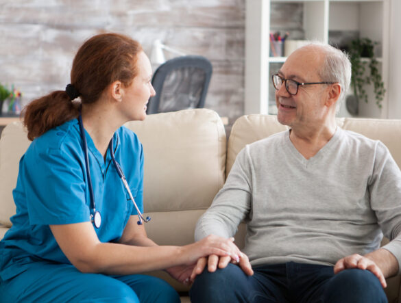 A health care professional speaking to a patient in their home.